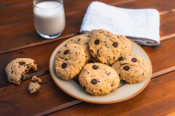 Pile of chocolate cookies with a glass of milk on a wooden table