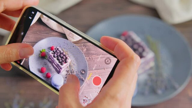 Person recording a video of velvet cake, holding a smartphone, a food blogger, photograph taking photos of delicious dessert served on plate, decorated with fruit and lavender, 4k video clip