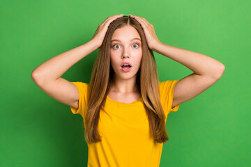 Photo of funky youngster teenager girl brown hair touch hands head open mouth speechless scared deadline homework isolated on green color background