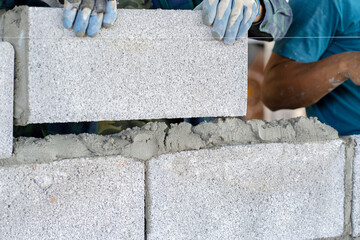 masonry worker make concrete wall by cement block and plaster at construction site