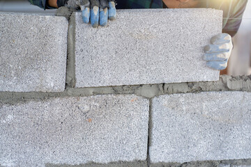 masonry worker make concrete wall by cement block and plaster at construction site