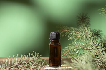 Cosmetic bottle with essential oil on green fir tree background. Beauty product for facial skin...