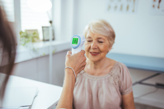 Temperature screening. Fevers measure forehead by infrared for patient in clinic during coronavirus epidemic. Doctor measures patient in mask temperature with contactless thermometer in clinic
