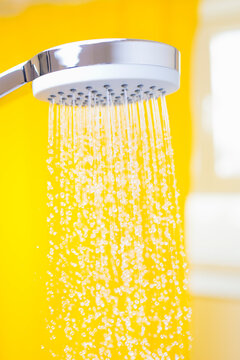 Close-up of flowing water drops from a shower head in a bright bathroom
