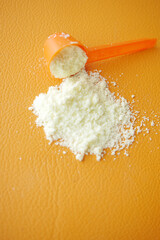 Close up of baby milk powder and spoon orange background 