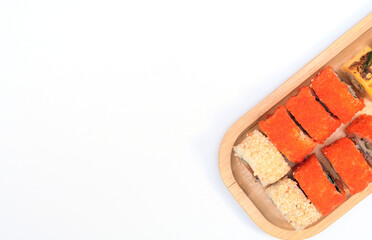 Delicious Japanese rolls with salmon, avocado, cucumber, cheese on wooden plate with selective focus on white background. Asian food concept. Healthy eating