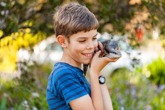 Happy tween boy with blue-tongued lizard outside in garden