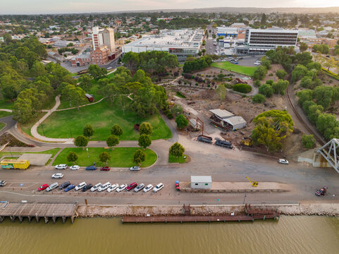 Aerial view of a wharf  and parkland alongside a dirty river