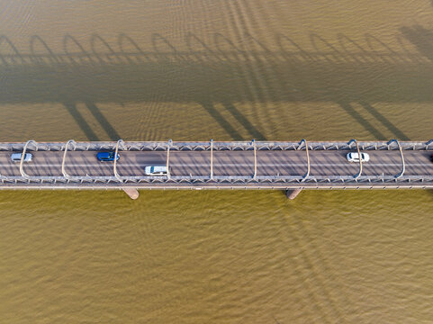 Looking down on traffic on a bridge crossing a wide brown river