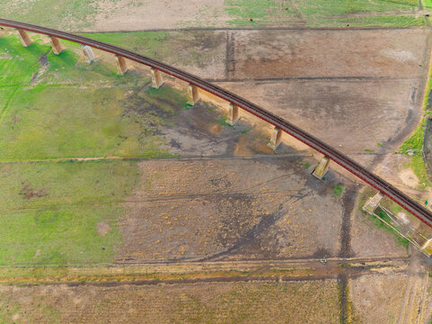 Looking down on a raised railway viaduct over farmland