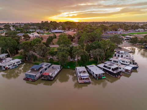 Aerial view of a house boat marina on a river with a sunset behind
