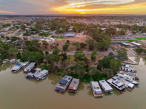Aerial view of a house boat marina on a river with a sunset behind