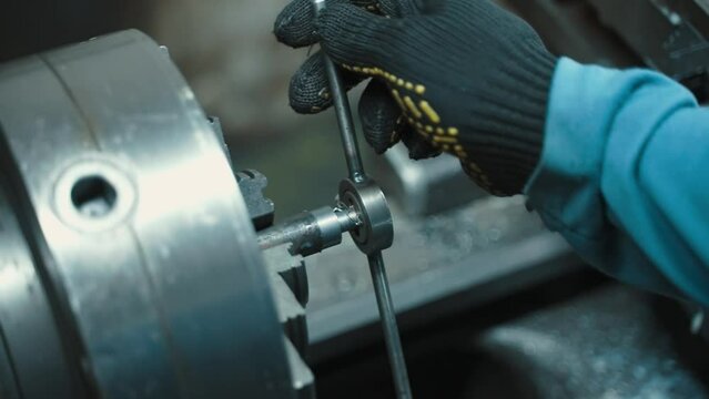 A man working on a lathe in a workshop cutting threads into parts