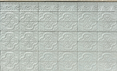 Gray painted ceramic tiles on a spanish house facade. Upper finish of the socle with Serlio and floral decorative motifs. 