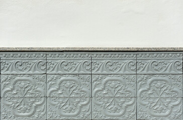 Socle of a spanish facade house with floral and Serlian decorative motifs. Gray painted ceramic tiles.