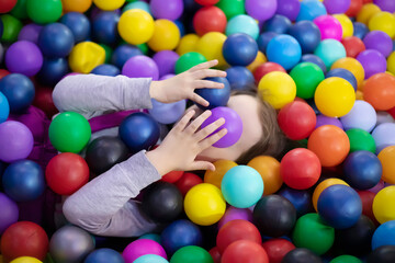 Little cute toddler girl play with plastic balls  in children playcenter. Toddler girl in Day Care Play Room