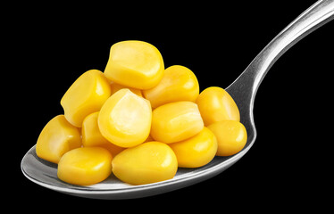 Delicious corn seeds in metal spoon, isolated on black background