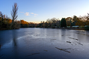 A frozen lake at sunset. There is ice on the surface of the lake in this winter scene. A cold...