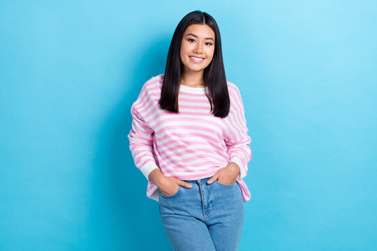 Photo of cheerful pretty young girl dressed pink pullover smiling walking arms pockets isolated blue color background