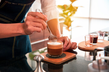 Fototapeta na wymiar man is pouring hot milk into coffee to make an espresso for a customer.