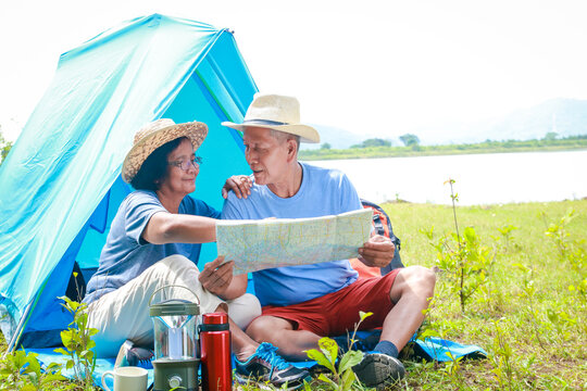 Asian elderly couple happy to travel in nature Set up a tent and camp in the forest. Tourism concept of the elderly in retirement age. Tourists and travelers trekking - Powered by Adobe