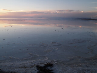 夕焼けとオレンジに染まる雲が反射するウユニ塩湖
