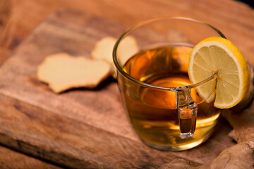 Hot ginger-infused cup on a white table with sliced ginger root in a bowl. Top view.