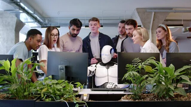 Portrait smart futuristic cyborg with artificial intelligence working in IT company using computer doing tasks. Group of people worker of office watching white robot solving problems online applauding