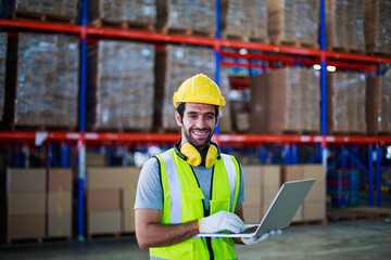 Man worker working holding laptop with Soundproof headphones for industry on package box in...