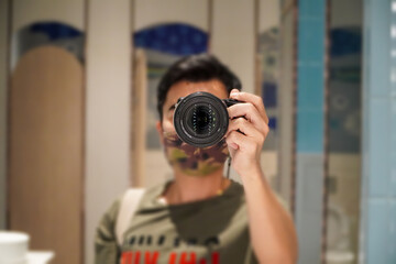 Young man taking pictures with his camera looking through the viewfinder from the bathroom mirror.Person pointing a camera lens at you