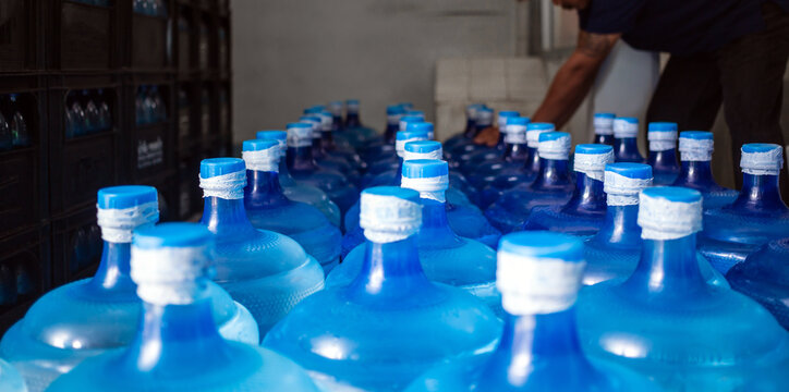 A large number of plastic blue gallons of drinking  water products in a drinking water plant that are arranged in a row waiting to be sold. drink water factory  business concept