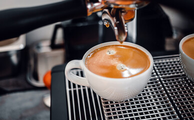 Coffee extraction from the coffee machine with a portafilter pouring coffee into a cup,Espresso poruing from coffee machine at coffee shop