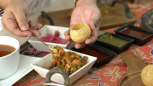 Close-up of Indian woman's hand showing how to eat Pani puri, which is to food culture of Indians, to Indian people and food concept.
