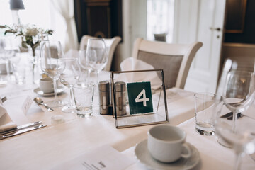 Wedding. Banquet. On festive tables with white tablecloths there are compositions of flowers, candles, cutlery, glasses, plates, menu cards and name plates