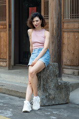 beautiful curly wight woman, sitting near Chinese house