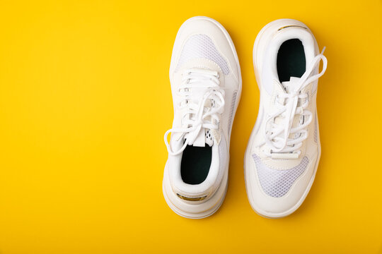 A pair of white shoes on a yellow background. White stylish sneakers. STREET STYLE.Sports concept, unisex, sports shoes, lifestyle, concept, product photo, levitation concept, streetwear.