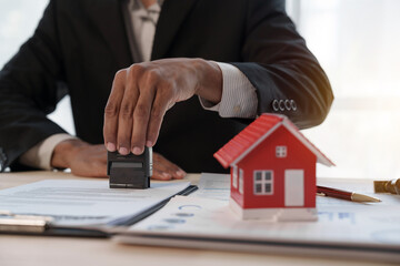 Credit approver, businessman in male suit and house toy model mockup Home loan mortgage approval concept. After signing the contract