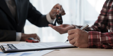 Fototapeta na wymiar Loan approver, businessman in suit, man giving car keys after car loan approval and contract signing