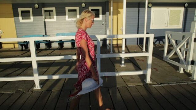 Australian travel freedom. Happy blonde woman walking at famous Busselton wooden jetty in Busselton, Western Australia with sunset light. Female tourist in iconic place. Summer season.