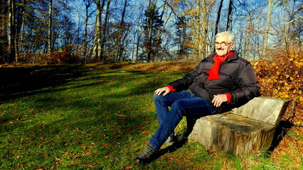 aktiver Senior genießt die Natur auf einer Bank auf der schwäbischen Alb im sonnigen Herbst