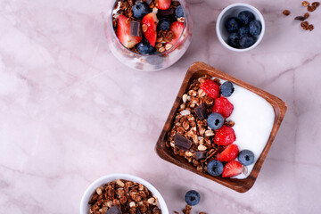 Yogurt with chocolate granola, strawberry and blueberry served in a bowl and a glass. Healthy breakfast. Top view