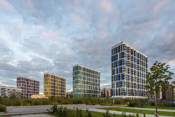 Four colorful high-rise residential buildings against a blue sky with clouds at sunset, St. Petersburg, Russia