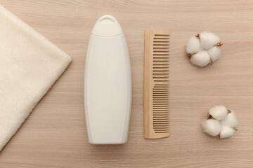 Fototapeta na wymiar White towel and white shampoo and white cotton flowers on a wooden surface.