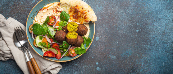 Middle Eastern Arab meal with fried falafel, hummus, vegetables salad with fresh green cilantro and...