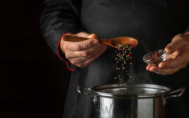Chef adds aromatic peppers to a pot of boiling water while cooking. Hotel kitchen concept with...