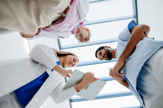 Team of doctors meeting at hospital corridor, low angle view.