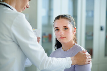 Close-up of doctor consoling unhappy teenage girl in her ambulance office.