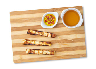 Grilled Rennet or Coalho cheese on a wooden board with sugar syrup and pepper isolated over white background