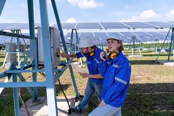 Maintenance engineer at solar farm trouble shooting looking at inverter control panel radio to team