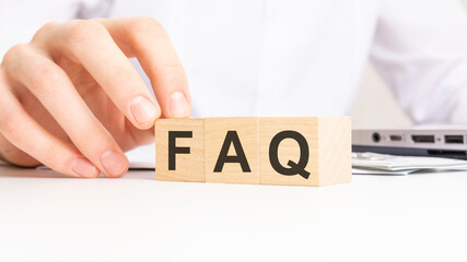 hand holding wooden cube with FAQ text on table background. financial, marketing and business...